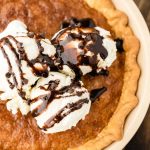 overhead view of a cookie pie piled with ice cream and fudge