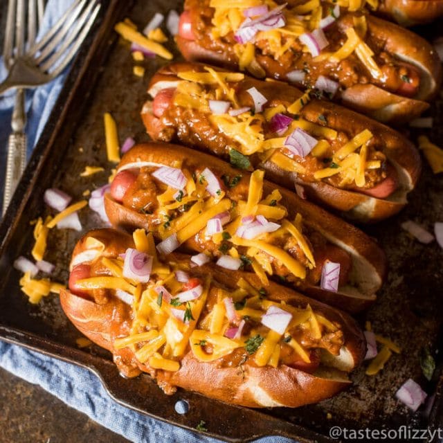 4 hot dogs on buns with chili sauce and cheese
