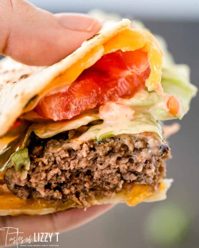 hand holding bite of quesadilla burger