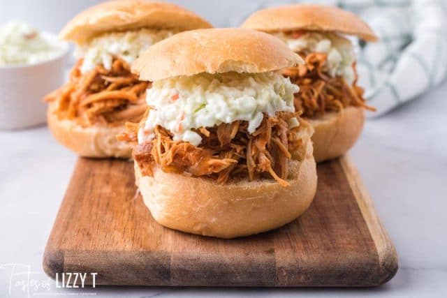 3 shredded chicken sandwiches on a cutting board