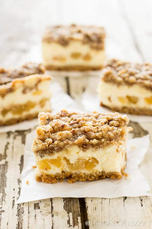 several caramel apple cheesecake bars sitting on sheets of white parchment paper