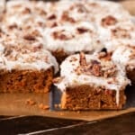 carrot cake bars sitting on a table, one on a spatula