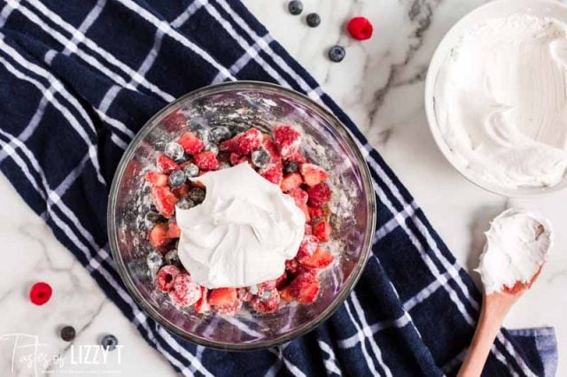 cool whip over cut berries in a bowl