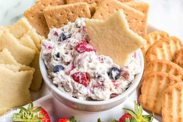 bowl of triple berry fruit dip with a star cookie in it and other cookies around it
