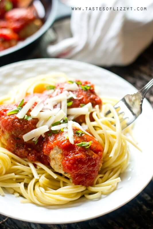 chicken Parmesan meatballs served on a white plate over a bed of cooked spaghetti