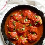 healthy chicken Parmesan meatballs simmering in a cast iron skillet