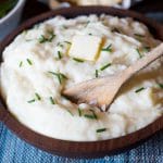 stirring a dish of rich and creamy mashed potatoes