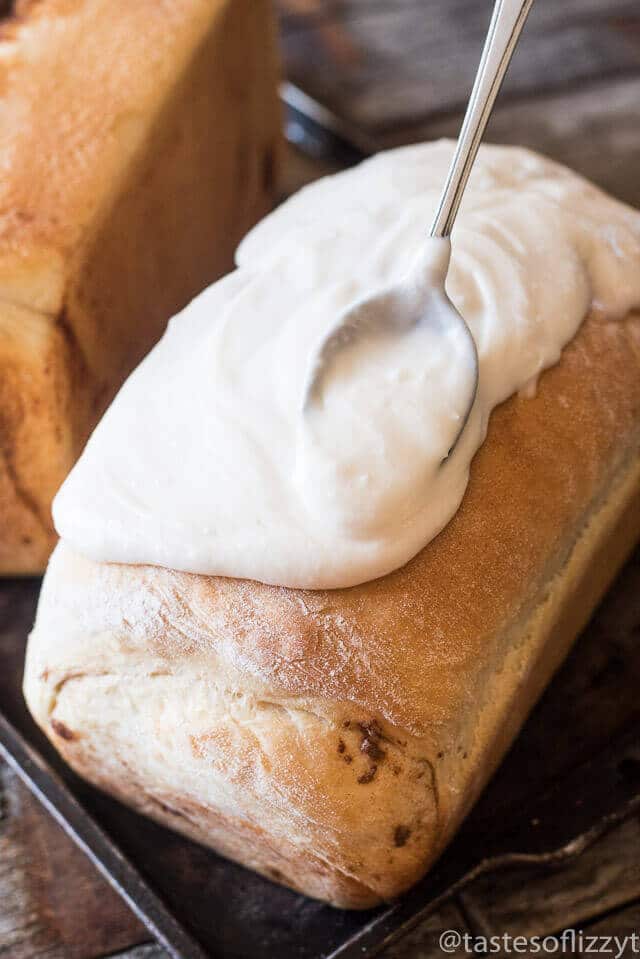 Spreading powdered sugar glaze on a loaf of cinnamon bread