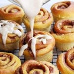 Pumpkin spice cinnamon buns being drizzled with icing