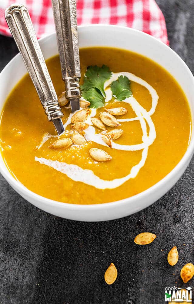 two spoons in a bowl of pumpkin apple carrot soup