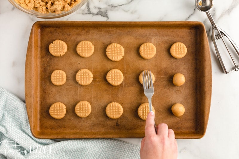 pressing fork onto peanut butter cookies