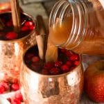 pouring spiced cranberry apple cider into a mug