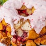 monkey bread on a plate with strawberries and glaze