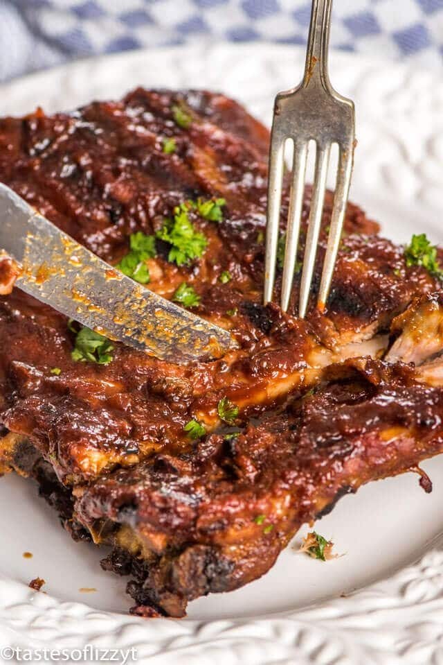 A close up of a plate of food with a fork, with Ribs