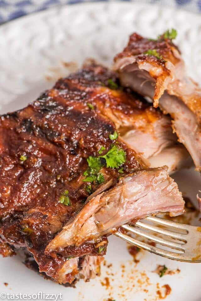 A close up of a plate of food with a fork, with Ribs