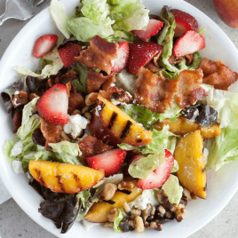overhead shot of dinner salad with grilled peaches, strawberries and bacon