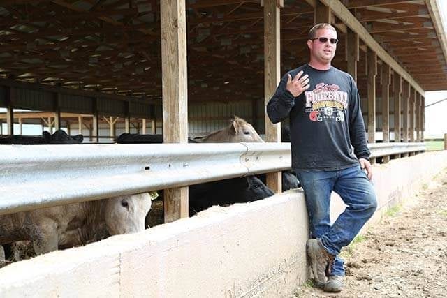 A man standing next to a fence, with Ohio Beef Council