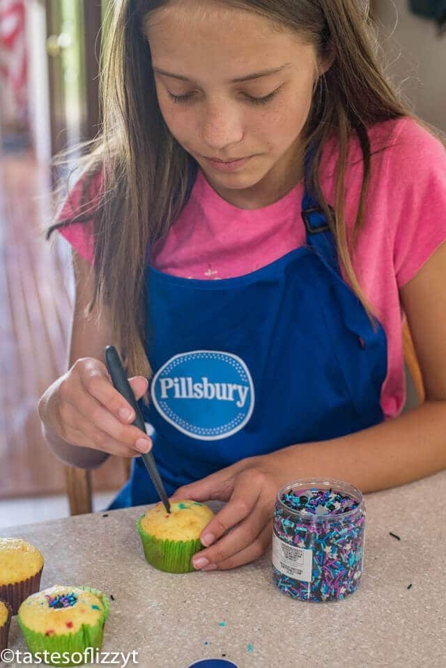 A woman sitting at a table making cupcakes