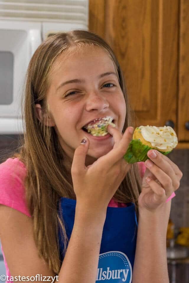 A little girl that is eating some food, with Cupcake