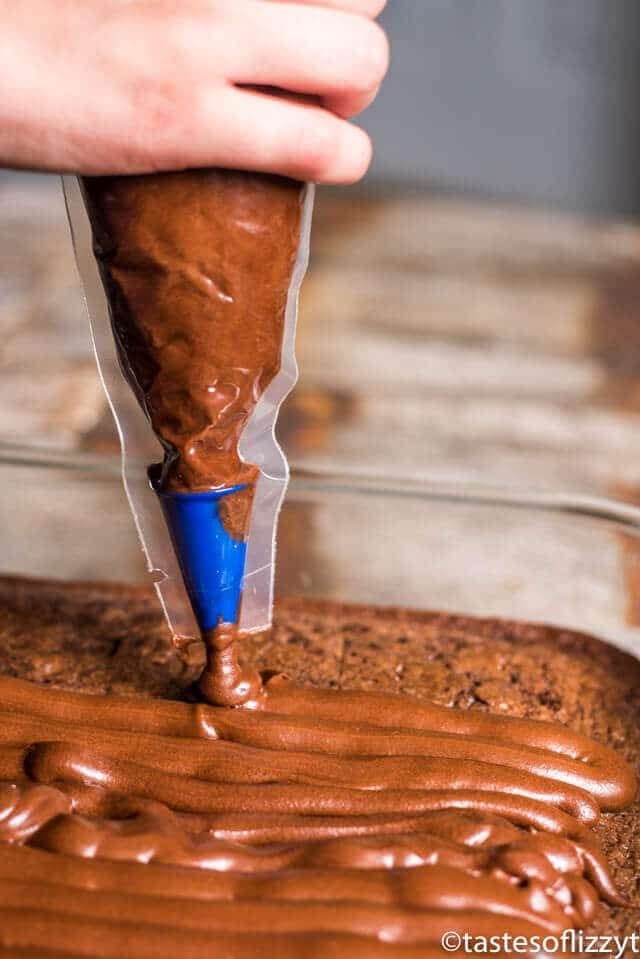 piping chocolate frosting on brownies