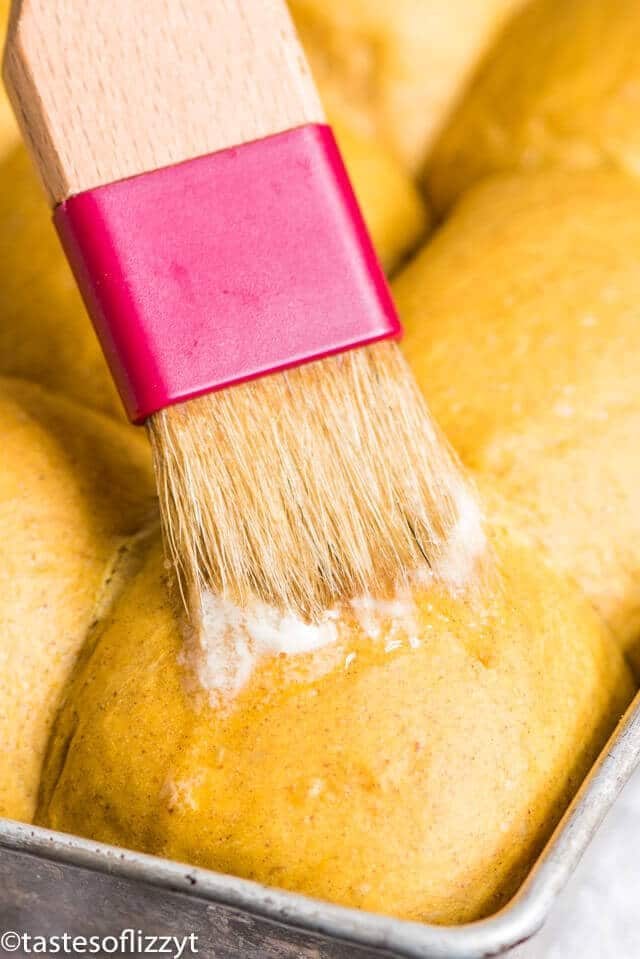 brushing butter over homemade pumpkin dinner rolls
