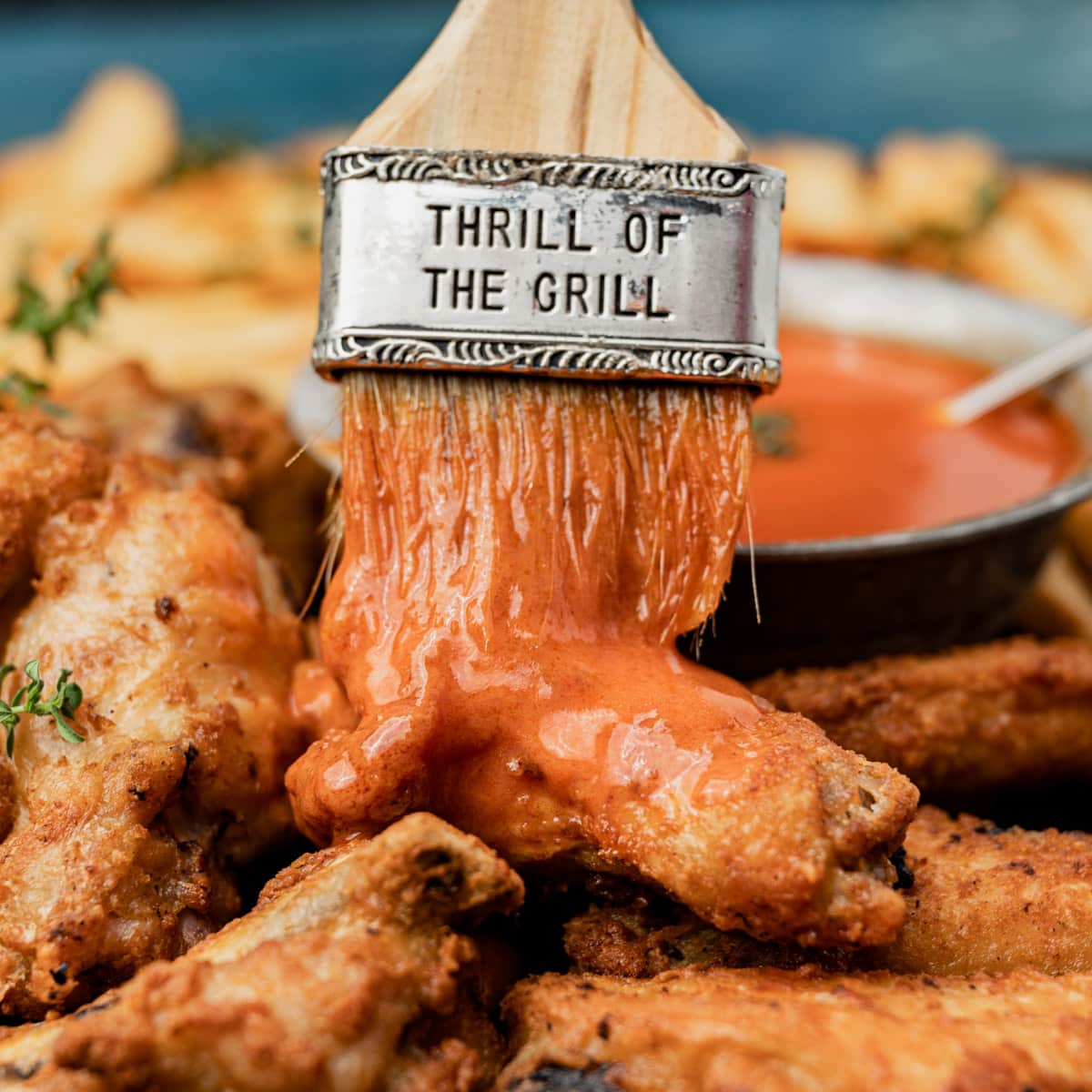 brushing buffalo sauce over chicken wings