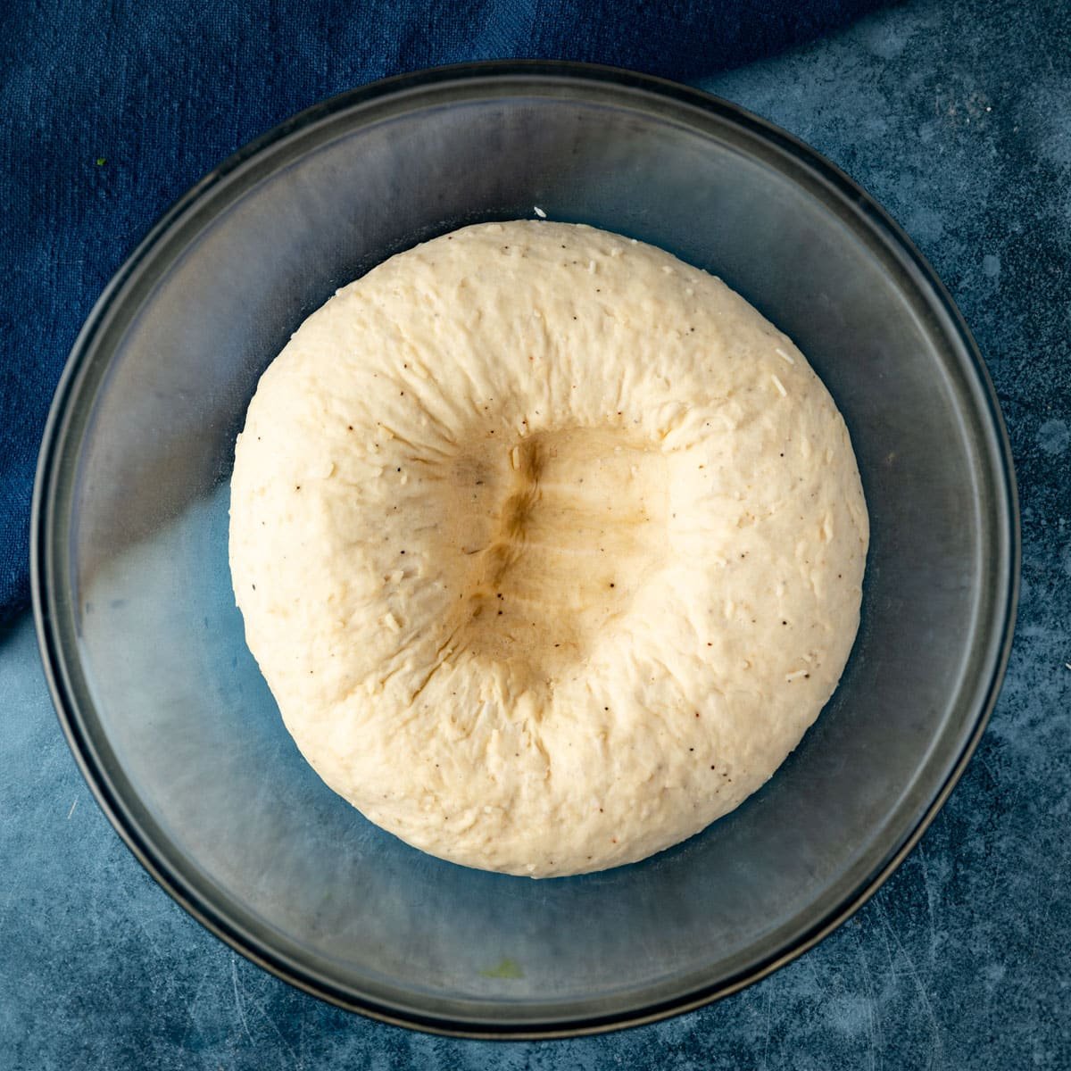 punched down bread dough in a glass bowl