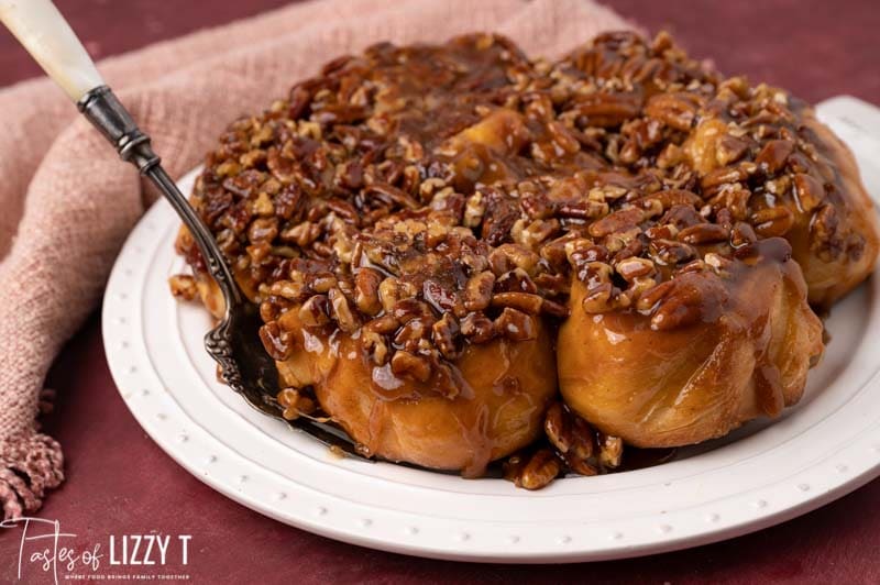plate of caramel pecan sticky buns with a serving spoon