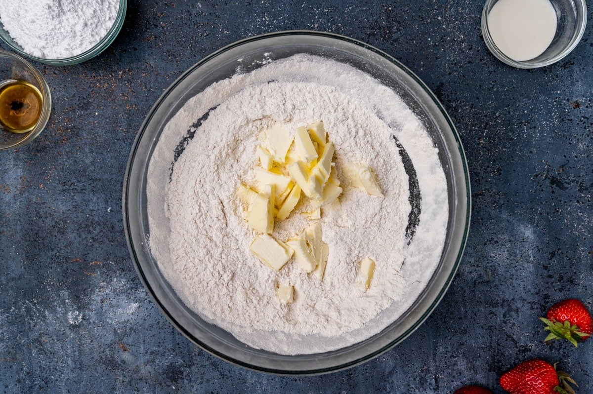 a bowl of flour with butter pieces sitting on top