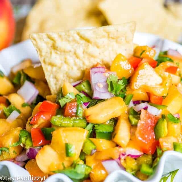 easy peach salsa in a bowl with a tortilla chip