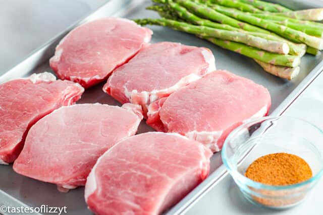 A tray of food on a table, with uncooked Pork chops