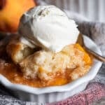 peach cobbler with biscuits in a bowl with ice cream
