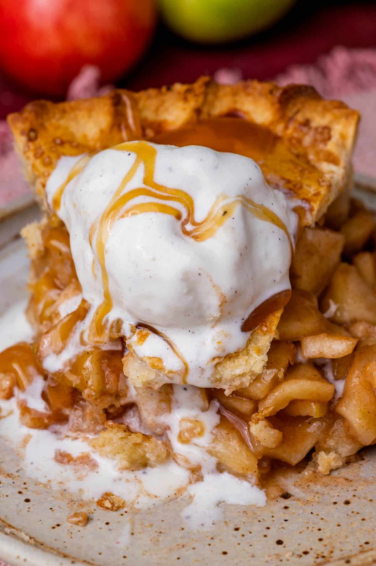 a piece of apple pie on a plate with ice cream and caramel