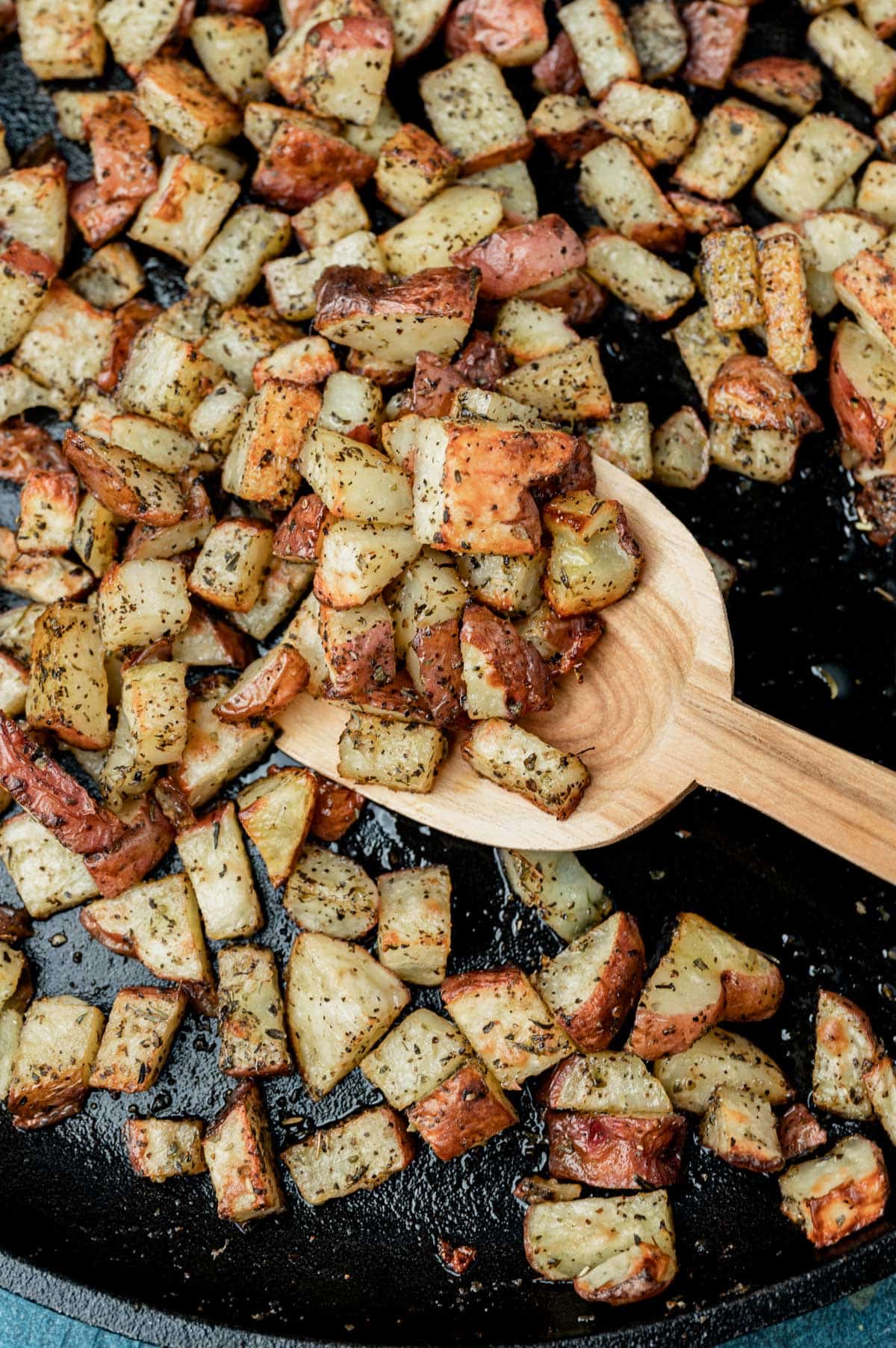oven roasted potatoes on a skillet with a wooden spoon