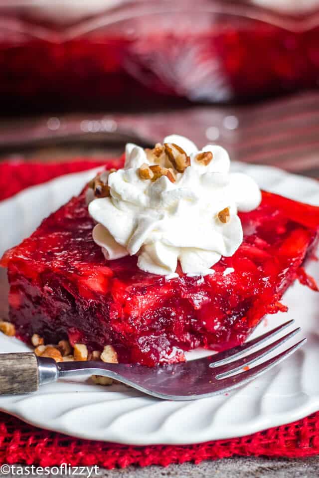 piece of cranberry jello with whipped cream and pecans