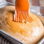 brushing butter on a loaf of bread