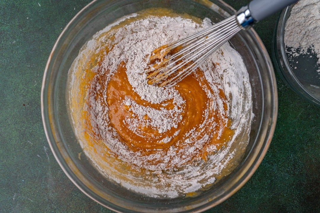 wet ingredients mixing into dry ingredients in a mixing bowl