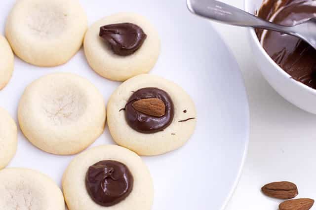 spooning chocolate into thumbprint cookies