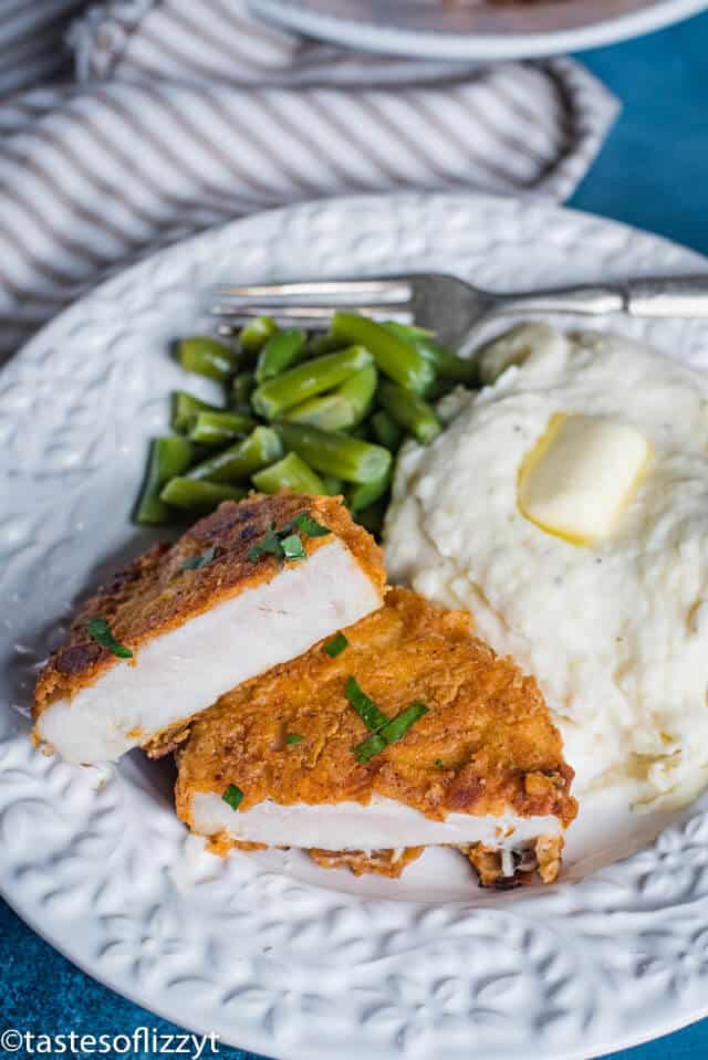 A plate of food with a pork chop, potatoes and green beans