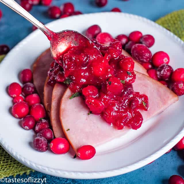 spoon putting cranberry sauce on ham