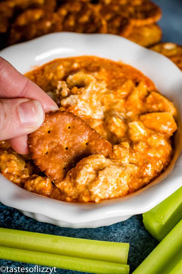 hand holding cracker in buffalo chicken dip