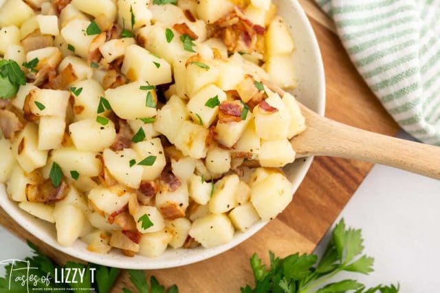 a bowl of potato salad with a wooden serving spoon