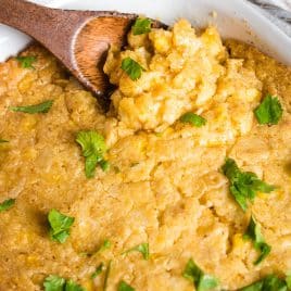 mexican street corn casserole in a pan with a wooden spoon