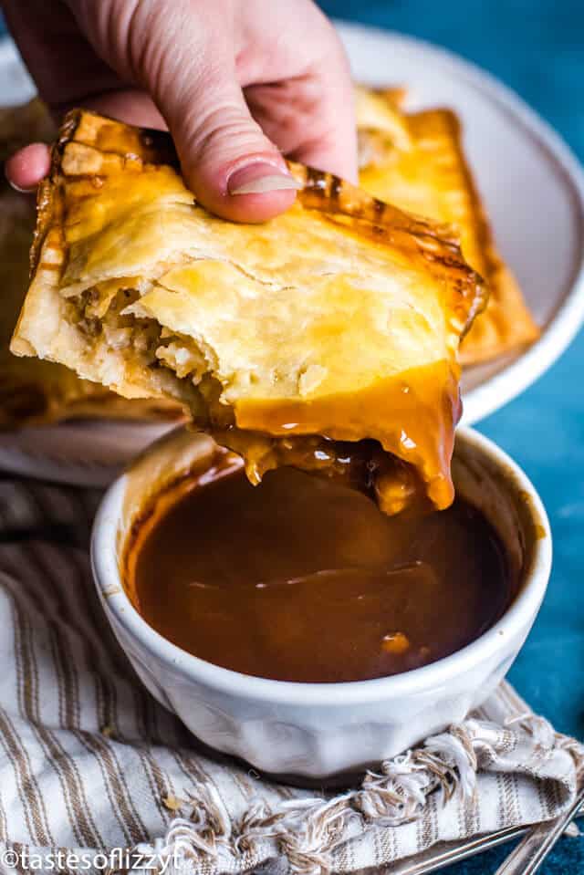 hand dipping sausage hand pies in gravy