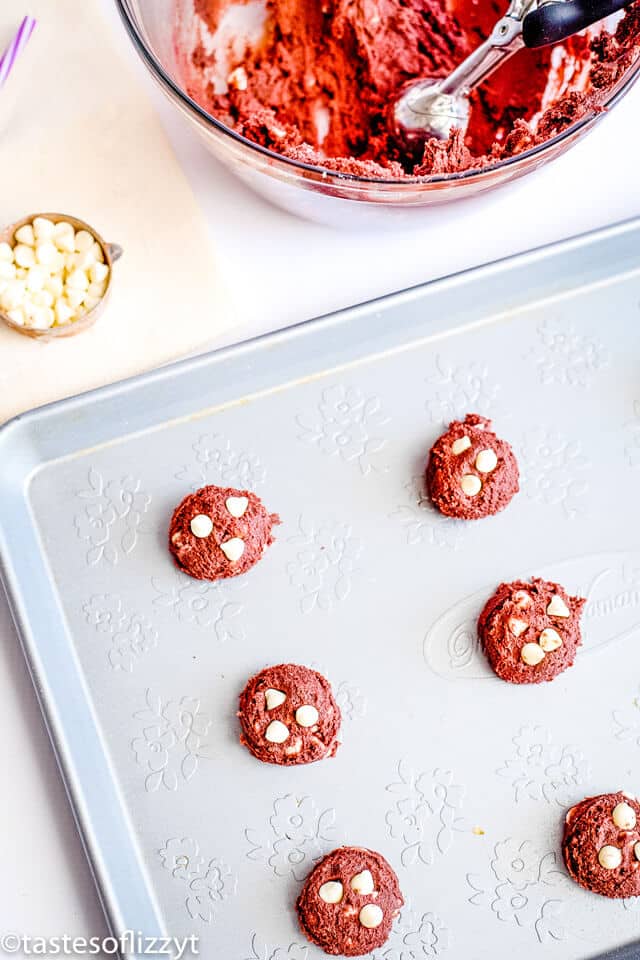 scoops of red velvet cookie dough on a baking sheet