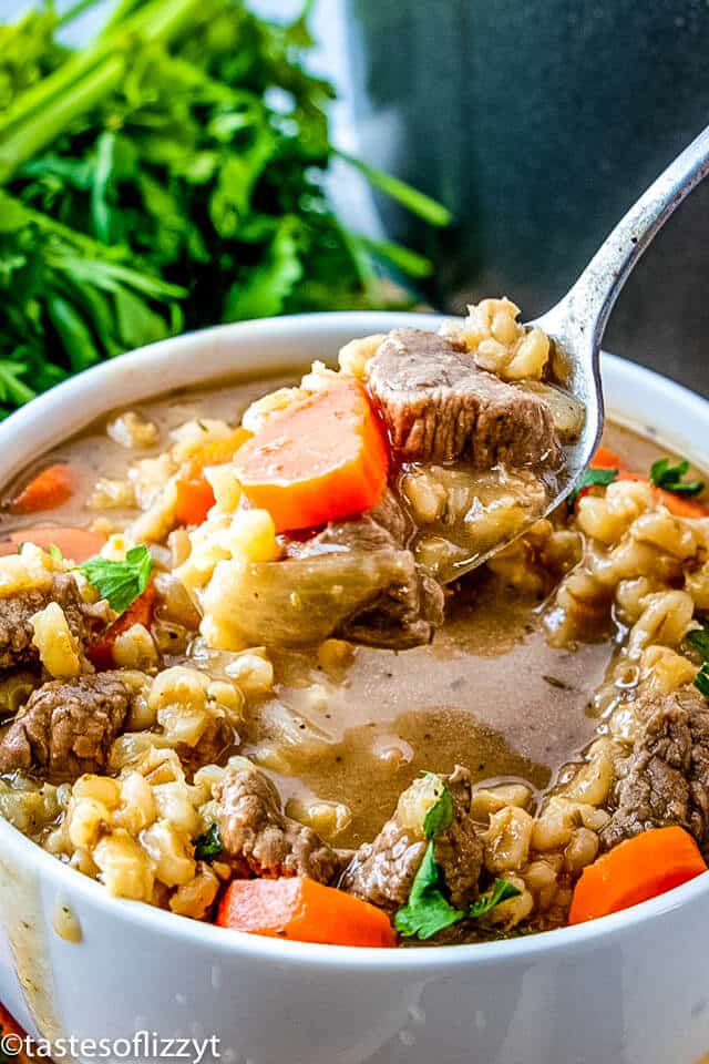 A bowl of beef barley soup with a spoon