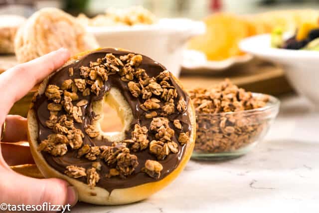 hand holding a bagel with granola