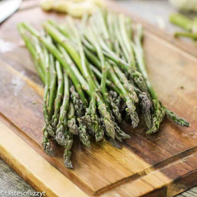 A wooden cutting board with asparagus