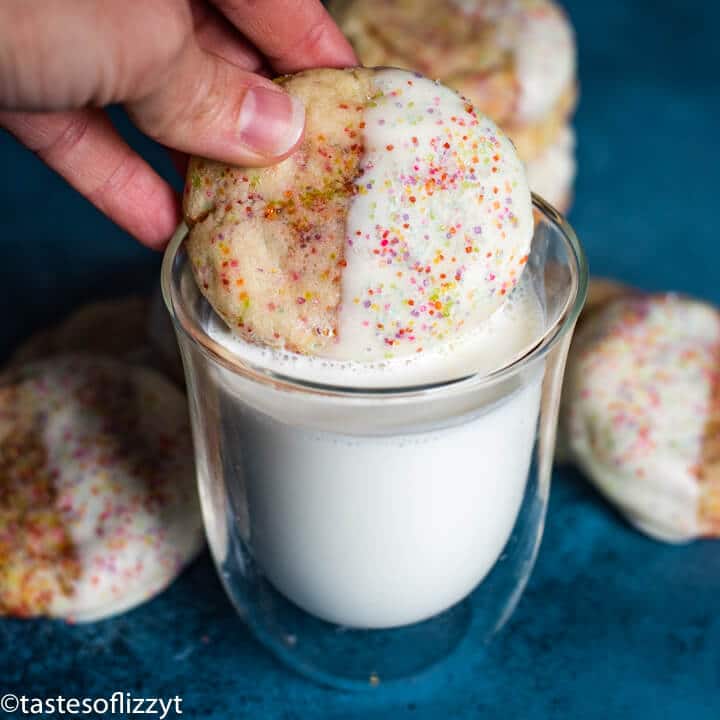 hand dipping a cookie in milk