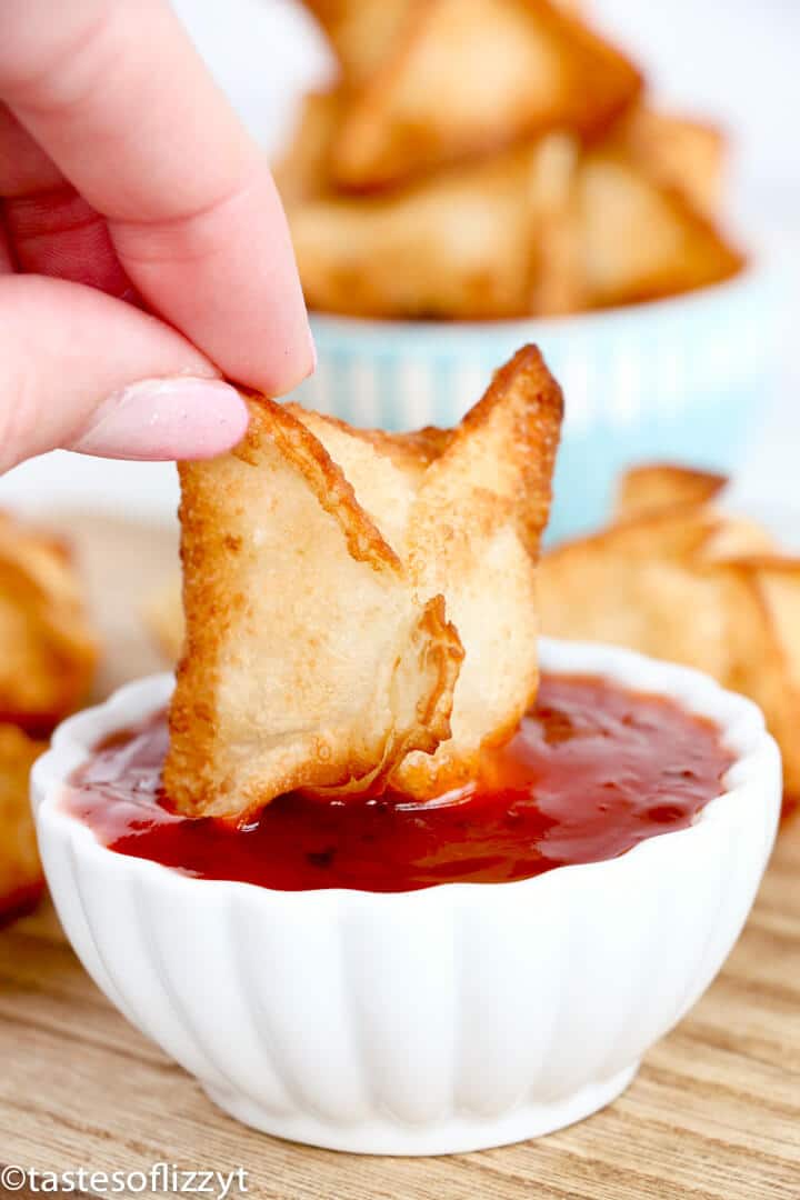 crab rangoon dipping in red sauce